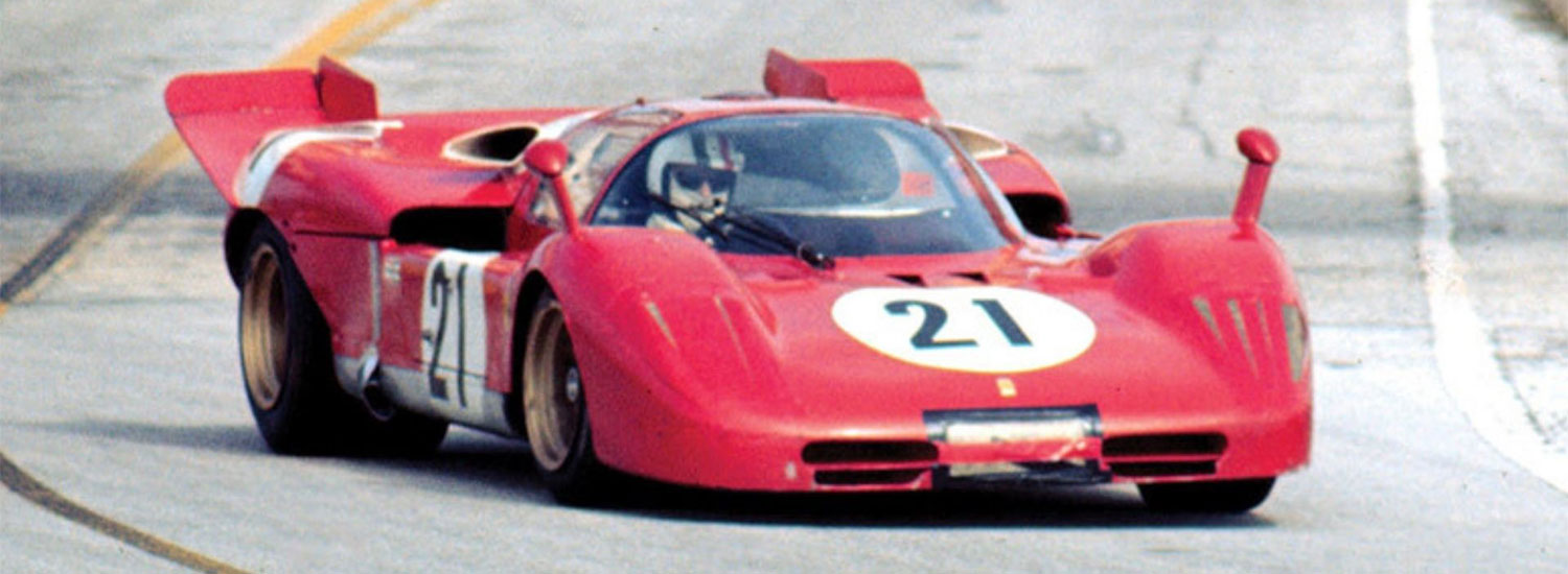 Historic red No. 21 race car speeds around the track at Sebring International Raceway.